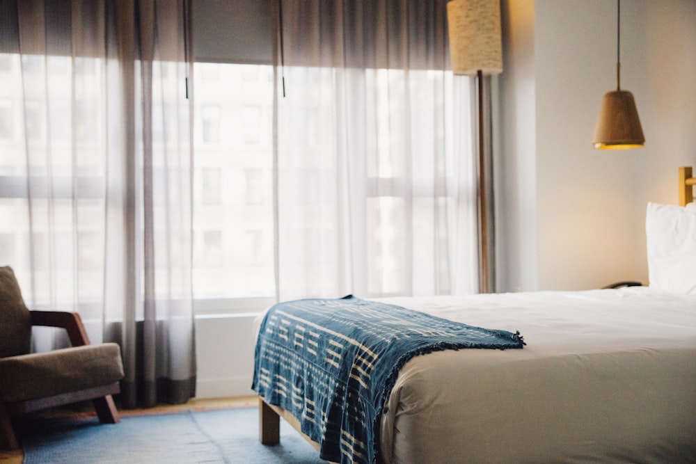 A sunlit hotel room with a made bed and soft neutral tones